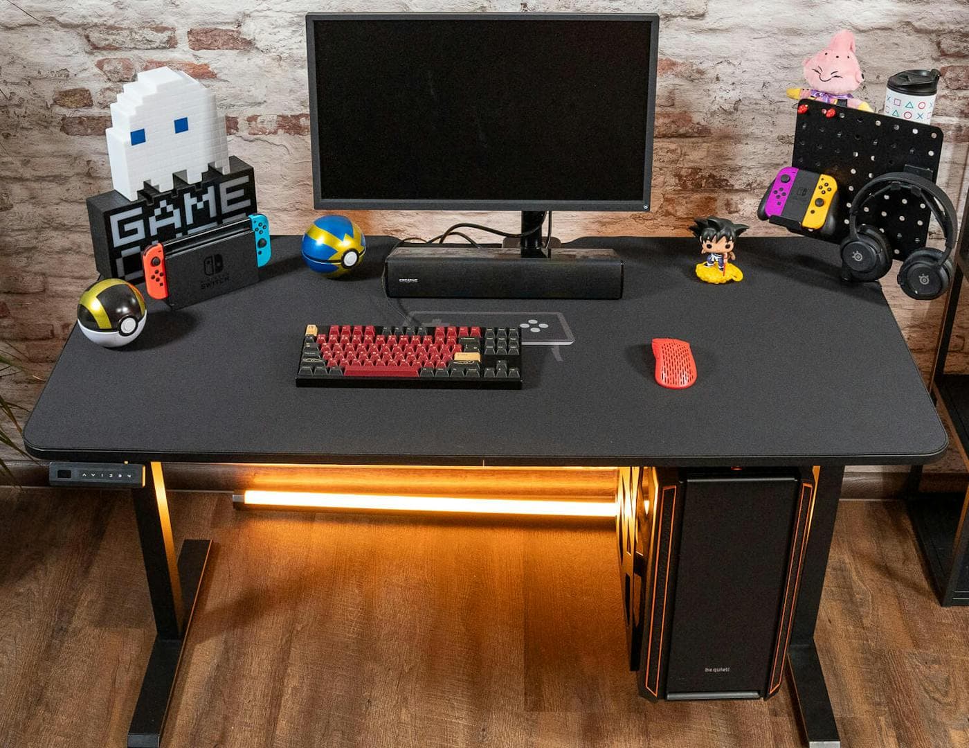 A complete gaming setup on a Leetdesk featuring a black deskpad with RGB lighting underneath, showcasing various accessories and a keyboard placed on the mauspad for a clean, professional look.