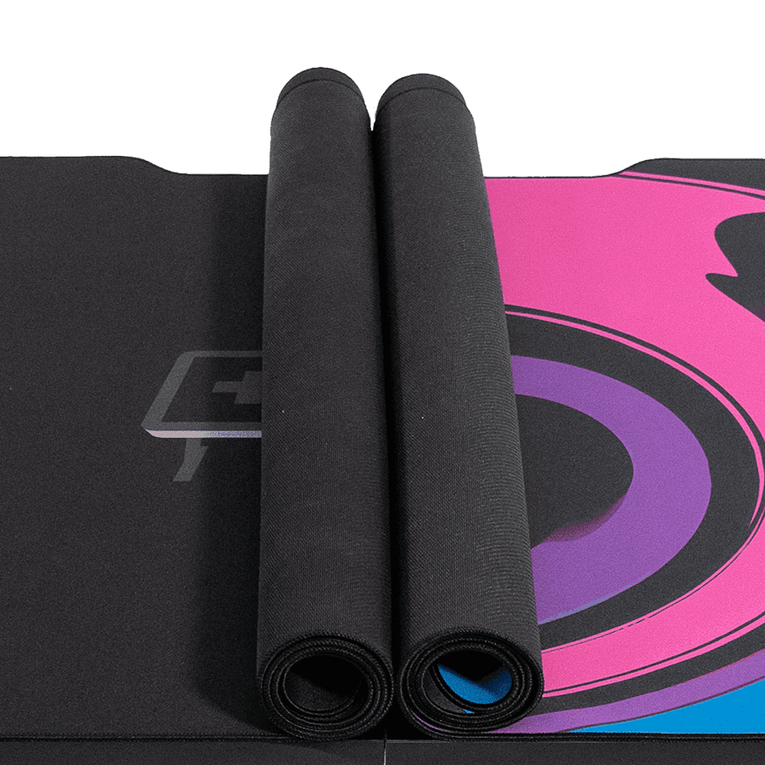 A black deskpad with a colorful swirl pattern on a height-adjustable Leetdesk, featuring dual mousepads rolled up on the tabletop. The mauspad covers a large portion of the desk surface for optimal use.