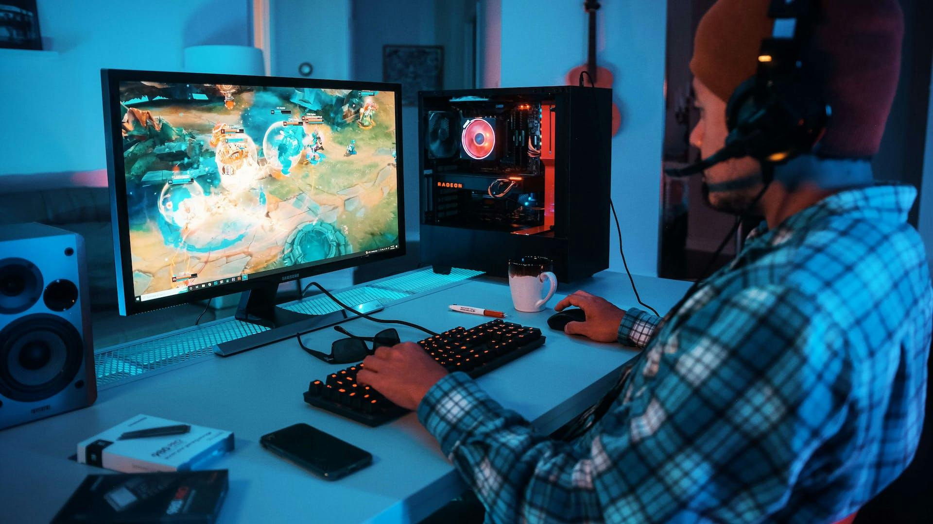 Eine Person sitzt an einem einfachen aber stylischen Gaming Setup mit Gaming PC, Monitor und LED Tastatur